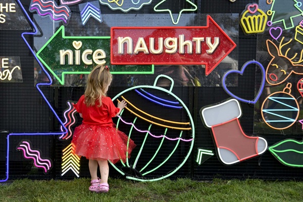 Girl with neon Christmas signs at Carols by Candlelight 2025