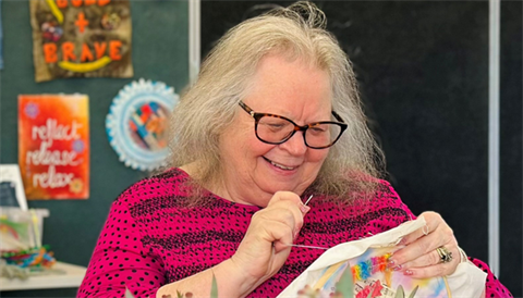 Denise looking at an embroidery hoop and sewing